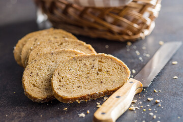 Sliced whole grain bread. Tasty wholegrain pastry with seeds on black table.