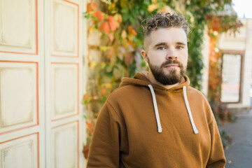 Outdoor portrait of young handsome smiling curly hair style man with beard in spring season - copy space and empty place for text