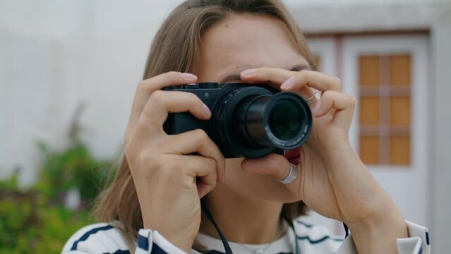 Closeup girl taking picture on analog camera. Beautiful tourist adjusting lens