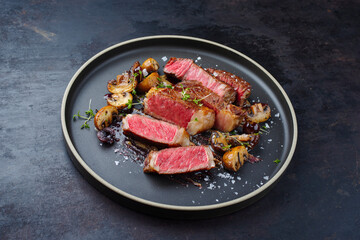 Modern style dry aged Wagyu rib eye beef steak with mushrooms in Amareno cherry and truffle sauce served as close-up on a Nordic design plate with text space