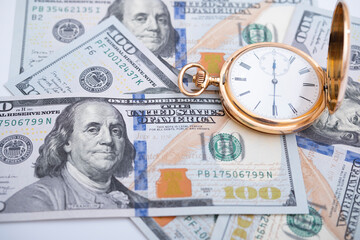 Macro shot of pocket watch face with 100 dollar bill Ben Franklin
money and time concept - old pocket watch on pile of american bill dollars