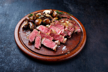 Traditional dry aged Wagyu rib eye beef steak with mushrooms and herbs served as close-up on a...