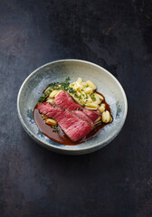 Traditionelles italienisches Chianina Roastbeef mit Gnocchetti-Sardi Nudeln in würziger Rotweinsoße serviert als close-up in einer Nordic Design Schale mit Textfreiraum 