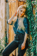 Beautiful blonde in demin shirt stay next to barn in a village