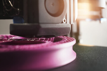 Detail view on nozzle of 3D-printer making a planetary gear part from pink plastic filament....