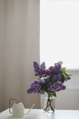 Home interior decor, bouquet of lilacs in a vase on table. Spring still life, interior details