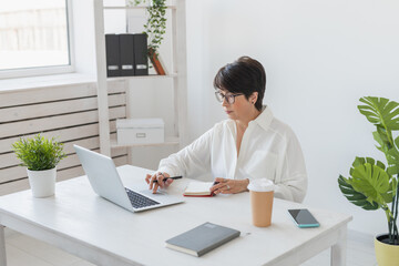 Attractive mature business woman working on laptop in her workstation - manager and office concept