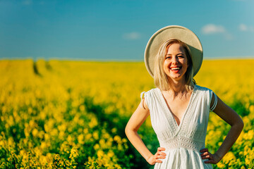 Naklejka na ściany i meble Beautiful woman in dress in rapeseed field