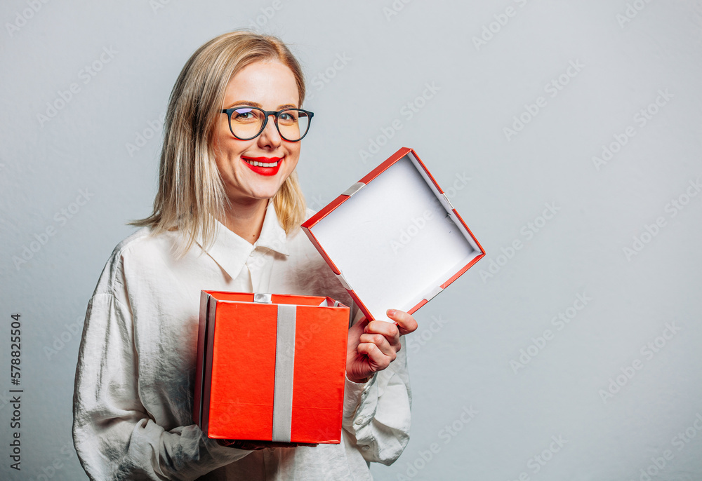 Poster portrait of beautiful blonde in white shirt with gift box on white background