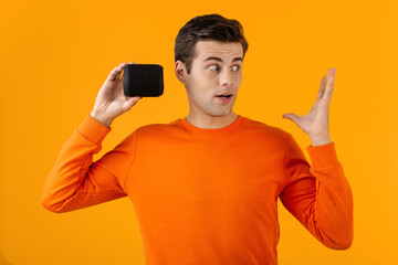stylish young man holding wireless speaker