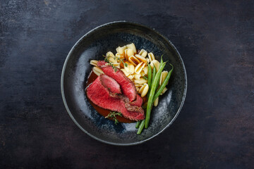 Traditional Italian chianina sliced roast beef with gnocchetti sardi pasta and beans in spicy red...