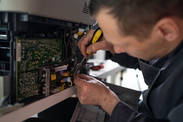 printer repair technician. A male handyman inspects a printer before starting repairs in a client's...