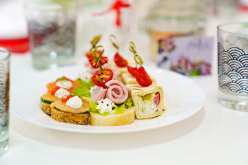 small sandwiches, rolls and burgers in a plate on the table.