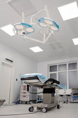 Spacious, well-equipped operating room, in the center of which there is an operating table, and an operating lamp is directed to it. The concept of health care, saving life.