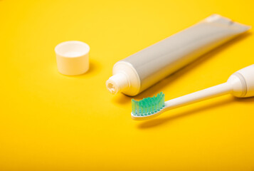 Electronic ultrasonic toothbrush and toothpaste on a yellow background. Items for dental care and caries prevention in the bathroom. Dentistry concept. Copy space.