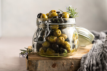 Green and black olives mix, in a glass jar. Delicious, marinated olives. 