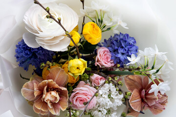 A bright spring bouquet of daffodils, hyacinths, roses, ranunculus, tulips, lilac and a branch of prunus. Hello spring. Happy birthday, happy Women's Day, happy wedding