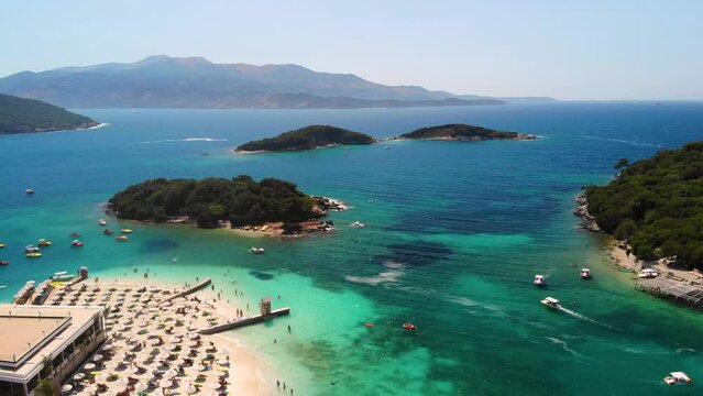 Aerial view exotic beach with turquoise water in Albania, Ksamil Islands. Tropical sandy paradise coastline shore with clear water. Summer vacation place with sun loungers. Balkans coast on Ionian sea