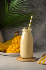 Bottle of mango, banana and yoghurt smoothie with a straw.
