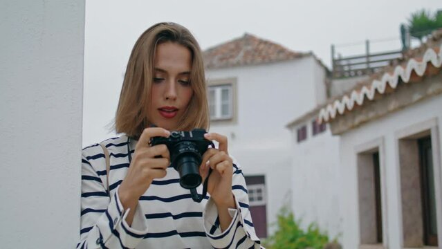 Girl taking old camera photos at whitewashed houses. Beautiful tourist travel