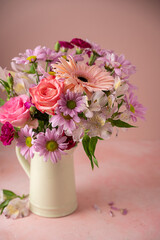Beautiful fresh spring flowers. Pink bouquet of flowers in vase, on pink background.