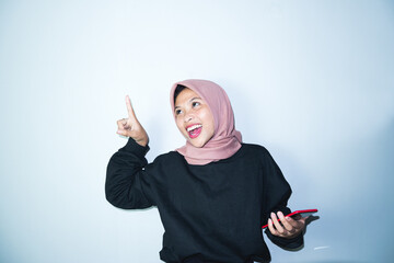 Beautiful asian hijab woman with hands pointing empty space presenting with smiling and confidently