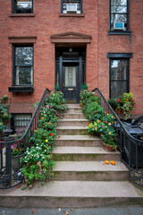 a brownstone building with a lot of blooming flowers on an iconic street in Manhattan, New York City - obrazy, fototapety, plakaty