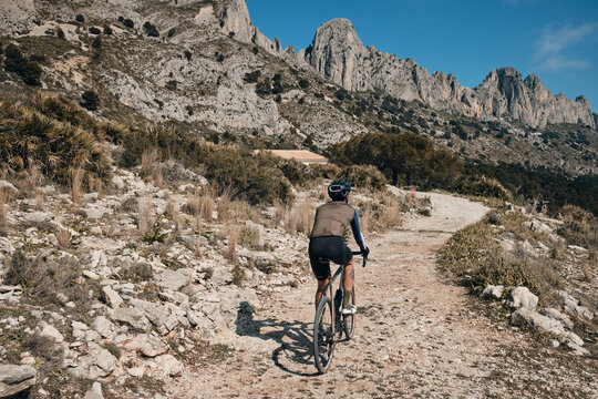 Men riding gravel bike on gravel road in mountains with scenic view  in Alicante region.Man cyclist  wearing cycling kit and helmet.Beautiful motivation image of an athlete.Serra de Bèrnia,Spain.