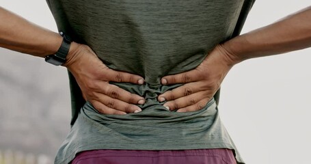 Rear view, closeup and back pain by man outdoors for fitness, training or morning cardio run. Hands, spine and injury for athletic male runner in nature while suffering with injured muscle or joint