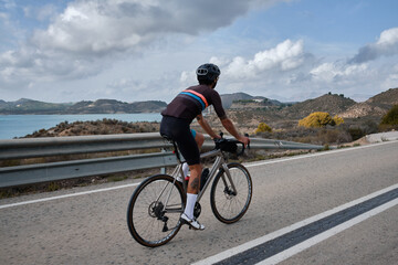 Man cyclist  wearing cycling kit and helmet.Man riding on bicycle in the mountains.Male cyclist is riding on bicycle in the mountains.Serra de B&egrave;rnia,Alicante, Spain