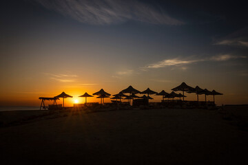 Umbrellas on the beach at sunrise in Marsa Alam, touristic resort in the Red Sea, Egypt
