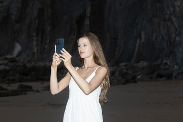 Woman hands holding mobile phone at sunset. Young woman taking photos with her cell phone in a beautiful amazing sunset over sea. Taking a picture on a smartphone during a vacation