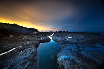 Beautiful sunset on the evening sea in Quang Nam province, Vietnam, volcanic rocks in the foreground