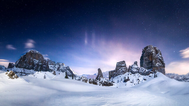 Starry night over the Cinque Torri on a snowy winter landscape in Cortina d'Ampezzo, Italy