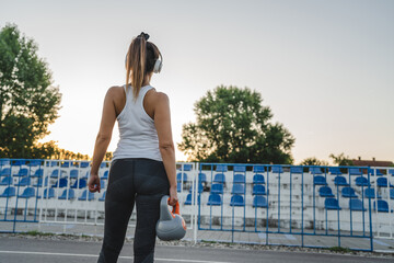 unknown caucasian woman hold kettlebell girya weight in stadium