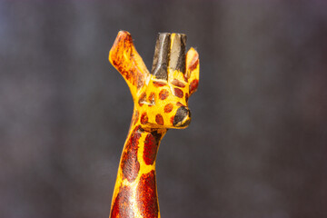 Wooden toy giraffe with long neck on dark background. Exotic animal from a zoo, wild nature. A mascot from Africa Safari. Figurine, figure. statue for home decor. Animal toys for lids children play.