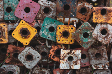 Old scaffold tubes are stored outside in a pile. Different colors yellow pink green tubes baseplates. Parts of the scaffolding. Scaffolding base vintage wallpaper. Standard workpiece scaffolds.