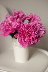 Pink peonies in vase on white chair