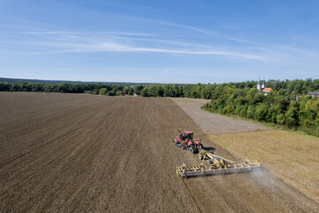 In the countryside, a large tractor sows a farmer's field with grain. Work in the field.