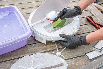 woman washing a trash can in a robot vacuum cleaner, planned maintenance