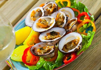 Fototapeta na wymiar Baked in oven European bittersweet clams with boiled potatoes, fresh vegetables and greens served with white wine
