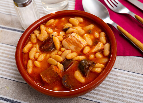 Delicious Fabada asturiana with stewed beans, pork, morcilla and chorizo served in traditional clay cazuela