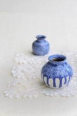 Fototapeta na wymiar Two blue ceramic small vases on a white napkin and white background, still life, close-up.
