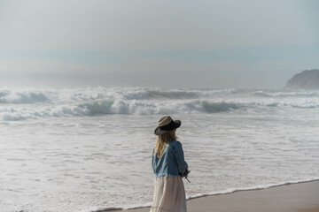 Donna di spalle con cappello passeggia sulle rive dell'oceano Atlantico