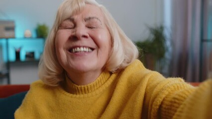 POV of senior grandmother making online selfie video call talking chatting via camera with family waving hand greeting hello at home. Communication, meeting. Mature woman make smartphone conversation - Powered by Adobe