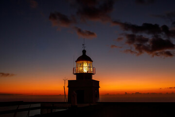 Ocean lighthouse during the sunset. Dramatic clouds on the background.