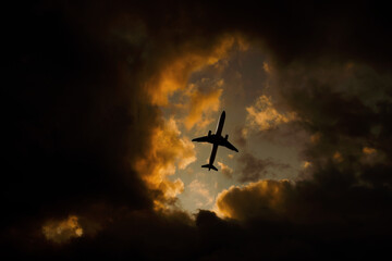 Airplane flies through orange dramatic clouds