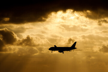 The plane flies over the sea in the sun rays.