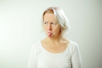 Pretty upset woman Adult woman with white hair is offended She shows her tongue expressively Her...