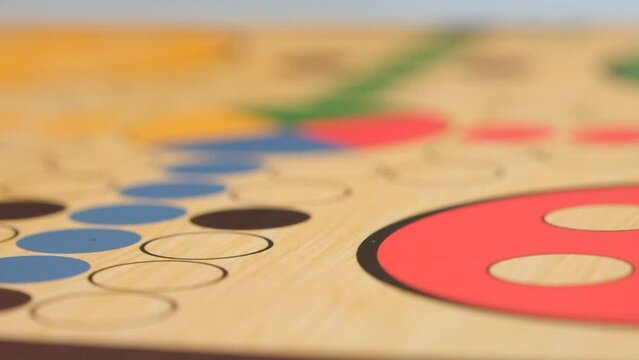 People play Ludo or Pachisi board games on beautiful wooden play board. An angry player sweeps the playing chips off the field Full HD slow motion resolution video.